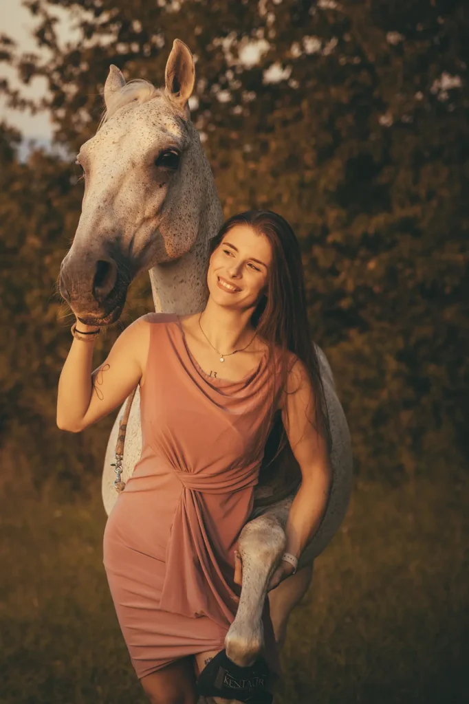 Žena odfotená so svojim koňom v prírode.